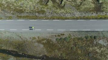 Professional Cyclists in Helmets are Racing on Mountain Road in Norway at Sunny Summer Day. Aerial Vertical Top-Down View. Drone is Flying Sideways video