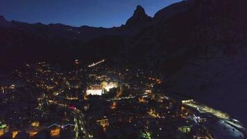 beleuchtet zermatt Dorf und Matterhorn Berg beim Winter Nacht. schweizerisch Alpen, Schweiz. Antenne Sicht. Drohne fliegt seitwärts zu das links, Kamera kippt oben video