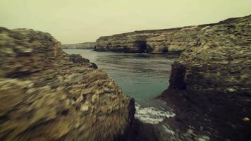 Low angle fast flying between rocks in the sea. Coastline with cliffs. video