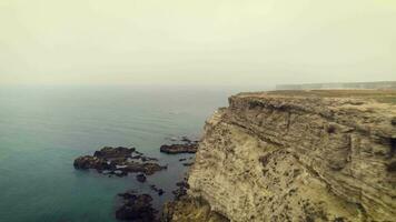 Low angle flying forward over cliff breakage along sea coastline. Aerial view video