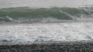 espirrando mar ondas com espuma e seixo costa. super lento movimento. video