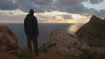 Silhouette von reifen Mann im Jacke und Deckel genießen Sonnenuntergang. video