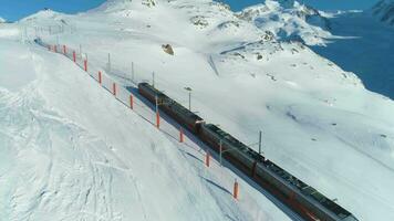 Zermatt, Svizzera - febbraio 12, 2019 ingranaggio ferrovia treno nel soleggiato inverno giorno. svizzero Alpi. Svizzera. aereo Visualizza. fuco è orbitante video