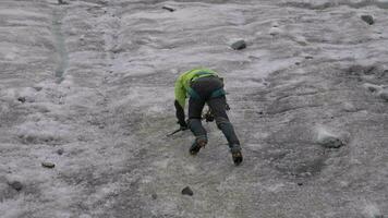 alpinista homem dentro grampos usando gelo machado para subir em íngreme gelo declive dentro montanhas. lento movimento video