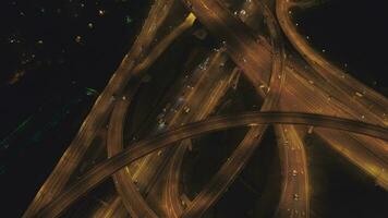 iluminado complexo estrada interseção e carros tráfego às noite. zangão é vôo para trás, Câmera é inclinação acima. aéreo vertical Visão video