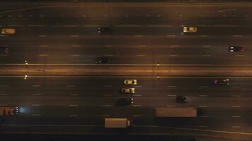 carros en iluminado autopista en ciudad a noche. aéreo vertical De arriba hacia abajo vista. zumbido es volador oblicuo. estableciendo Disparo video