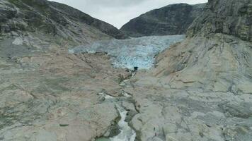 Derretendo nigardsbreen geleira dentro Noruega. pedras e água fluxo. aéreo visualizar. zangão é vôo para trás e para cima video