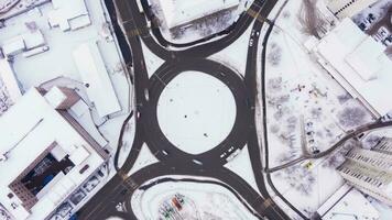 tráfico circulo en el ciudad y carros a invierno día. redondo la carretera intersección. aéreo vertical De arriba hacia abajo vista. hiper lapso. zumbido moscas hacia arriba y gira video