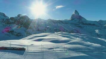 Matterhorn Berg und Zahn Eisenbahn Zug im sonnig Winter Tag. schweizerisch Alpen. Schweiz. Antenne Sicht. Drohne fliegt seitwärts video