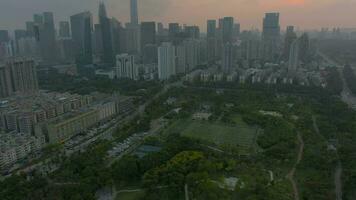 Shenzhen stad Bij zonsondergang. wolkenkrabbers van futiaan wijk. China. antenne visie. onthullen schot. dar vliegt naar voren, camera kantelt omhoog video