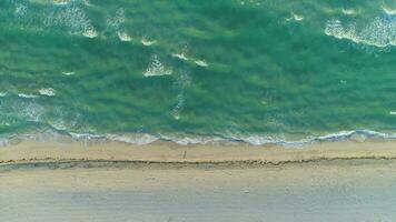 oceano com ondas e arenoso de praia dentro ensolarado manhã. aéreo vertical Careca Visão video