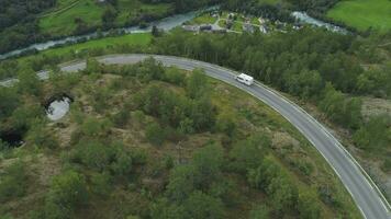 blanco casa rodante coche es yendo en país la carretera en Noruega en otoño día. arboles y ciudad. aéreo vista. zumbido es volador oblicuo video