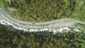 Car is Going on Country Road in Mountain Ravine in Norway in Summer Day. River and Green Hill Slope. Aerial Vertical Top-Down View. Drone is Flying Sideways video