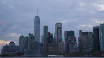 Manhattan urbano horizonte a nublado noche. nuevo York ciudad. ver desde el bote. cámara se inclina abajo. medio Disparo video