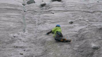 alpinista uomo nel ramponi sosta lui stesso mentre scorrevole su ghiaccio pendenza di utilizzando ghiaccio ascia nel montagne. lento movimento video