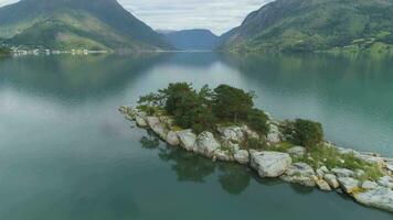 faible niveau en volant plus de île dans fjord avec vert montagnes sur Contexte. lustrefjorden, Norvège. réflexion dans l'eau. aérien révéler voir. drone est en volant avant, caméra est basculant en haut video