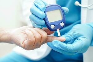 Asian doctor using digital glucose meter for check sample blood sugar level to treatment diabetes. photo