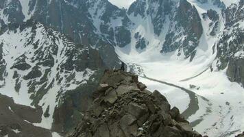 deux grimpeurs sur de pointe de rock. enneigé montagnes. aérien voir. drone est en orbite video