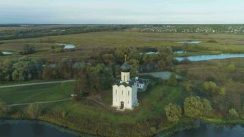 vit kyrka av de förbön på de nerl flod på solig kväll. Vladimir område, Ryssland. antenn se. Drönare är kretsande runt om, kamera är lutande ner video