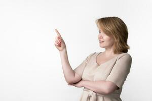 Woman in dress standing on white background, looking where is looking and where finger is pointing photo