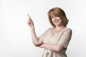 Blonde mature woman wearing casual dress looking at camera with pleasant smile, standing on white photo