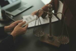 Business and lawyers discussing contract papers with brass scale on desk in office. Law, legal services, advice, justice and law concept picture with film grain effect photo