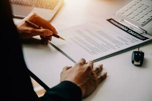 A car rental company employee is handing out the car keys to the renter after discussing the rental details and conditions together with the renter signing a car rental agreement. Concept car rental. photo