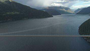 hoog hardanger suspensie brug aan de overkant de hardangerfjord met voorbijgaan auto in Noorwegen. fjord en bergen. antenne visie. dar is vliegend zijwaarts video