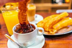 típico Español churros servido con taza de caliente chocolate en Sevilla, España foto