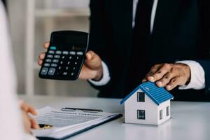 Accountant, businessman, real estate agent, Asian business woman handing keys to customers along with house after customers to sign photo