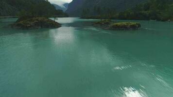 turquesa lovatnet lago. verde ilhas e montanhas dentro verão dia. Noruega. aéreo baixo nível revelar visualizar. zangão é vôo frente rápido, Câmera inclina acima video