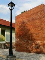 garden lamppost against the background of red brick wall, trees, clear sky photo