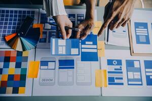 Close up ux developer and ui designer brainstorming about mobile app interface wireframe design on table with customer breif and color code at modern office.Creative digital development agency photo