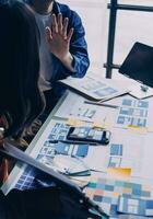 Close up ux developer and ui designer brainstorming about mobile app interface wireframe design on table with customer breif and color code at modern office.Creative digital development agency photo