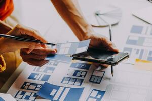 Close up ux developer and ui designer brainstorming about mobile app interface wireframe design on table with customer breif and color code at modern office.Creative digital development agency photo