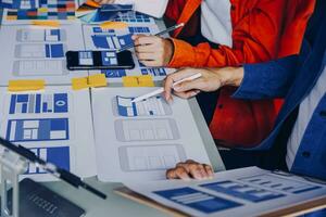 Close up ux developer and ui designer brainstorming about mobile app interface wireframe design on table with customer breif and color code at modern office.Creative digital development agency photo