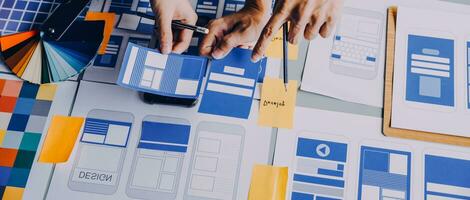 Close up ux developer and ui designer brainstorming about mobile app interface wireframe design on table with customer breif and color code at modern office.Creative digital development agency photo