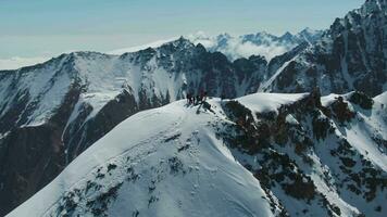 alpinistes sur Haut de enneigé Montagne dans ensoleillé journée. aérien voir. drone est en orbite dans le sens horaire video