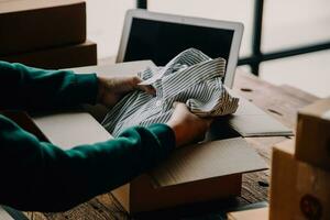 Emprendedora de pequeñas empresas o mujer asiática independiente que usa una computadora portátil con caja, joven mujer asiática de éxito con su mano levantada, caja de embalaje de marketing en línea y entrega, concepto de pyme. foto