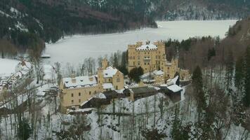 Hohenschwangau Castle and Alpsee Lake in Winter Day. Mountains and Forest. Bavarian Alps, Germany. Aerial View. Wide Shot. Drone Flies Backwards and Upwards video