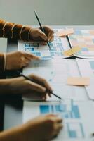 Close up ux developer and ui designer brainstorming about mobile app interface wireframe design on table with customer breif and color code at modern office.Creative digital development agency photo