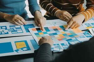 Close up ux developer and ui designer brainstorming about mobile app interface wireframe design on table with customer breif and color code at modern office.Creative digital development agency photo