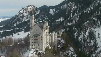 Neuschwanstein Castle on Rock in Winter Day. Mountains and Forest. Bavarian Alps, Germany. Aerial View. Medium Shot. Drone is Orbiting Counterclockwise, Flies Upwards video