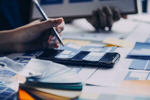 Close up ux developer and ui designer brainstorming about mobile app interface wireframe design on table with customer breif and color code at modern office.Creative digital development agency photo