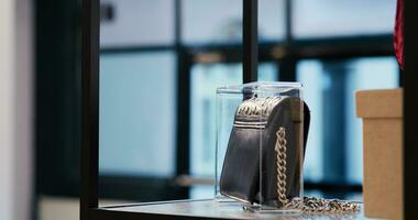 Selective focus of trendy black bag in empty modern boutique, filled with multiple racks with fashionable clothes and trendy accessories. Shopping mall equipped with stylish merchandise photo