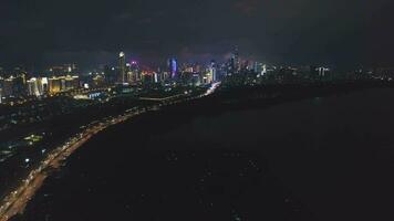 Shenzhen beim Nacht. Futian Kreis städtisch Horizont und Shenzhen Bucht. Guangdong, China. Antenne Sicht. Drohne fliegt seitwärts, Neigung oben video