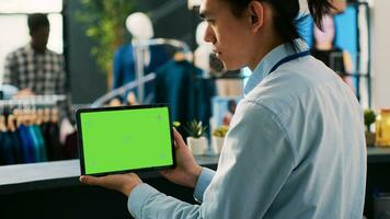 Store manager analyzing tablet computer with chroma key green screen mock up display, working in modern boutique. Asian employee holding digital device in shopping centre. Technology concept photo