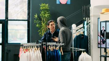 African american robber trying to sneak stolen shirt being caught by store security guard in modern boutique. Bodyguard asking thief to return stylish merchandise or will call the police photo