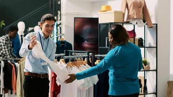 African american customer shopping for casual wear, discussing outfit material with boutique manager. Shopaholic woman buying fashionable clothes in clothing store. Fashion concept photo