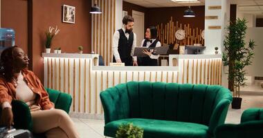 hotel gerente Listo a discutir fiesta paquete opciones y comodidades potenciar con cansado turista después largo vuelo. recurso personal empleados preparando invitado habitación, trabajando en elegante recepción vestíbulo foto